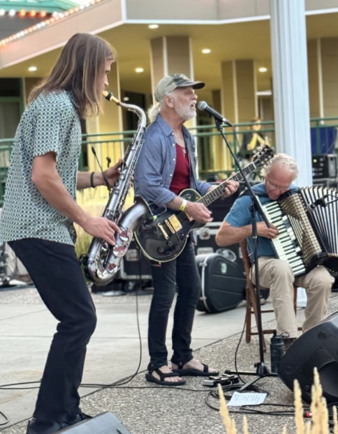 Musicians performing with saxophone, guitar, and accordion